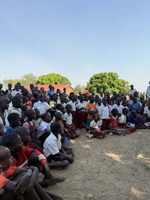 Children sitting outdoors for a school assembly