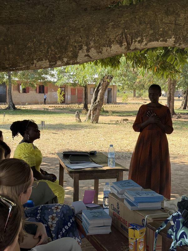 Children in class, hands raised, following an English lesson